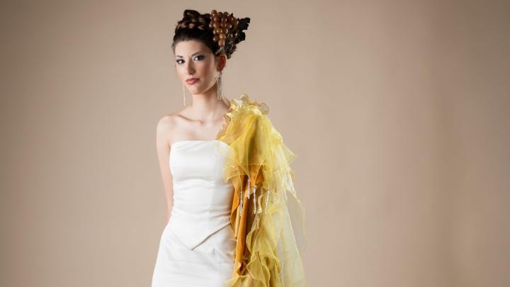 Giovane modella in in piedi, con elegante abito bianco, su sfondo neutro