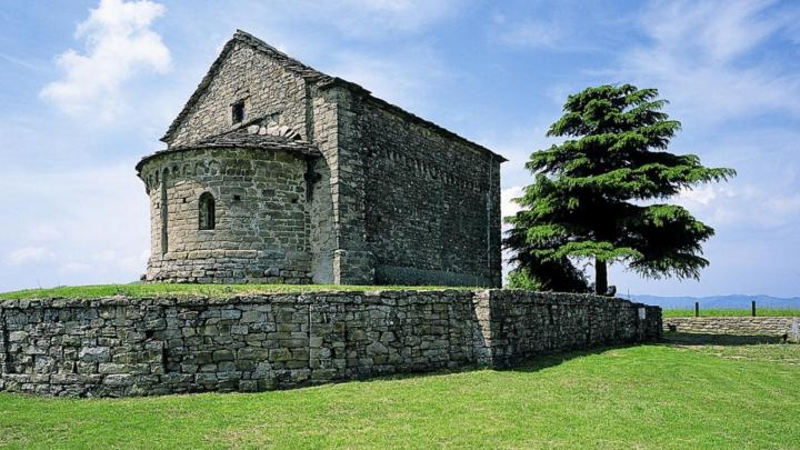 Bergolo, cappella romanica di San Sebastiano, esterno con abside prato e albero