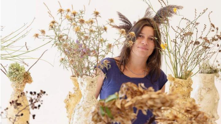 Ritratto fotografico delliartista Chiara Camoni da www.fondazionezegna.org Donna a mezza figura tra composizioni di fiori e foglie essiccati e intrecciati