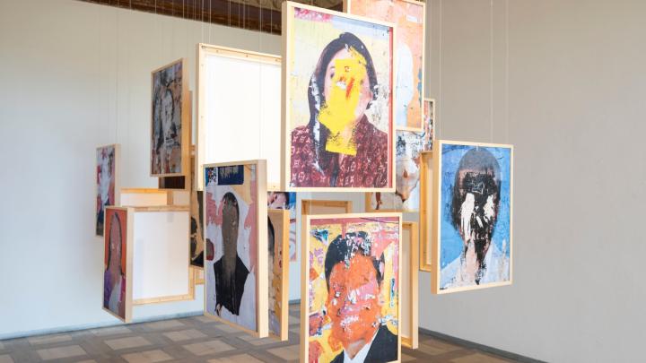 Foto di Perottino, particolare, con allestimento della mostra, dal sito della Fondazione Sandretto Re Rebaudengo Tele con volti dipinti appese con fili al centro di una stanza