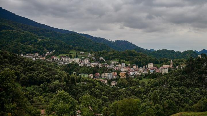 Centro abitato in una valle verdeggiante, cielo nuvoloso 