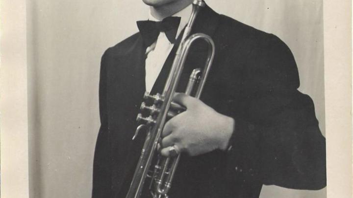 Particolare di ritratto fotografico d'epoca in bianco e nero: giovane uomo vestito in smoking con in mano una tromba