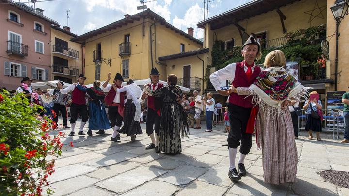 Ballo di donne e uomini in costume folkloristico in piazza a Limone Piemonte
