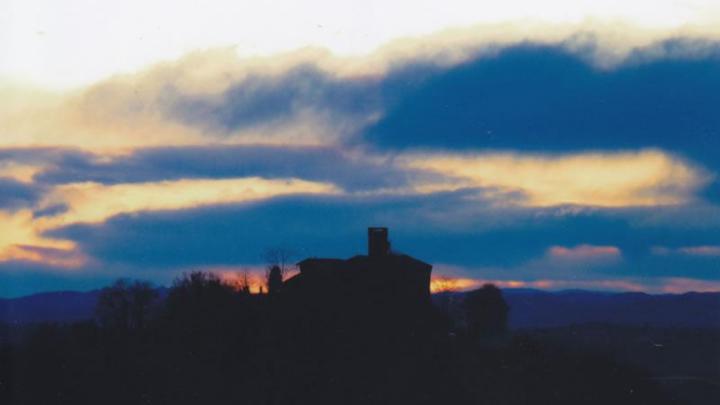 Immagine dal sito: www.comunemonteuroero.cn.it Profilo di castello cin torretta su una collina al tramonto