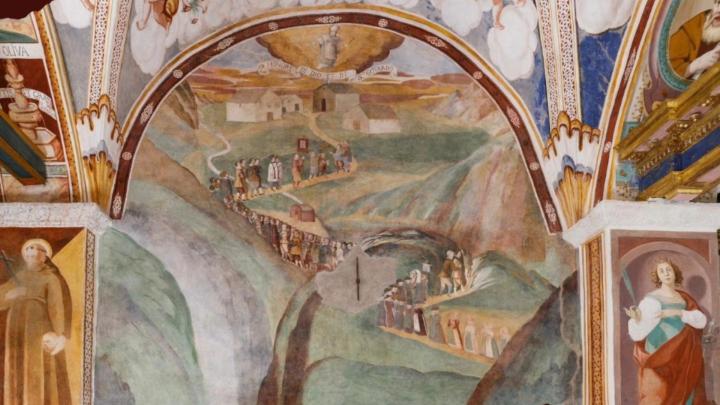 Fotografia di affreschi antichi con processione di pellegrini e santi entro nicchie