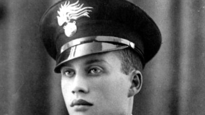 Particolare di foto ritratto in bianco e nero della prima metà del Novecento, con volto di giovane carabiniere con berretto rigido recante simbolo dell'arma del Carabinieri