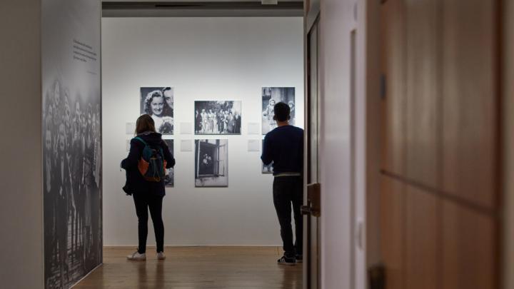 Un ragazzo e una ragazza osservano fotografie in bianco e nero sulle pareti di una sede espositiva