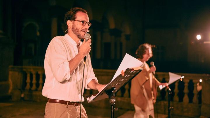 Fotografia: due attori recitano in piedi con microfoni in una chiesa