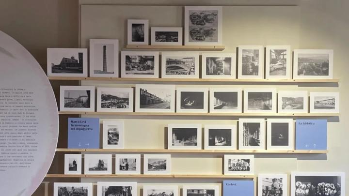 Particolare dell'allestimento di una mostra con fotografie in bianco e nero su scaffali e didascalia