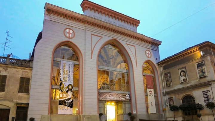 Particolare di fotografica con facciata neogotica recante tre grandi finestroni ogivali, stendardi dell'Anno francescano 2026 