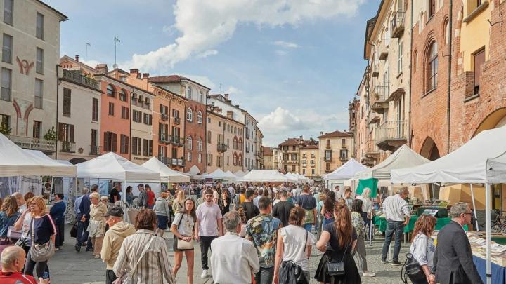 Foto di piazza del centro storico di Savigliano con bancarelle e avventori