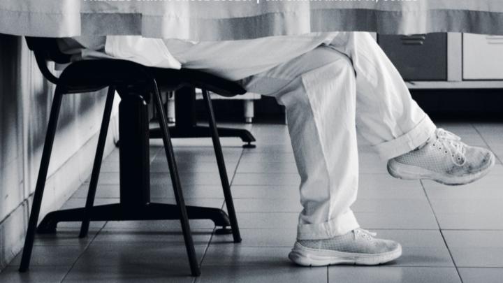 Particolare della locandina con foto di Marco Sasia Particolare di foto in bianco e nero con gambe di persona dai pantaloni chiari seduta