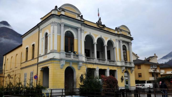 Facciata di teatro con loggia, sfondo di montagne  